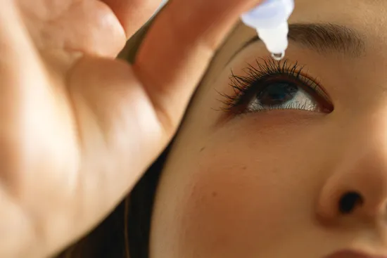 photo of woman putting eyedrops in eyes