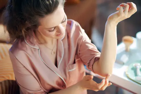 photo of woman applying cream to elbow